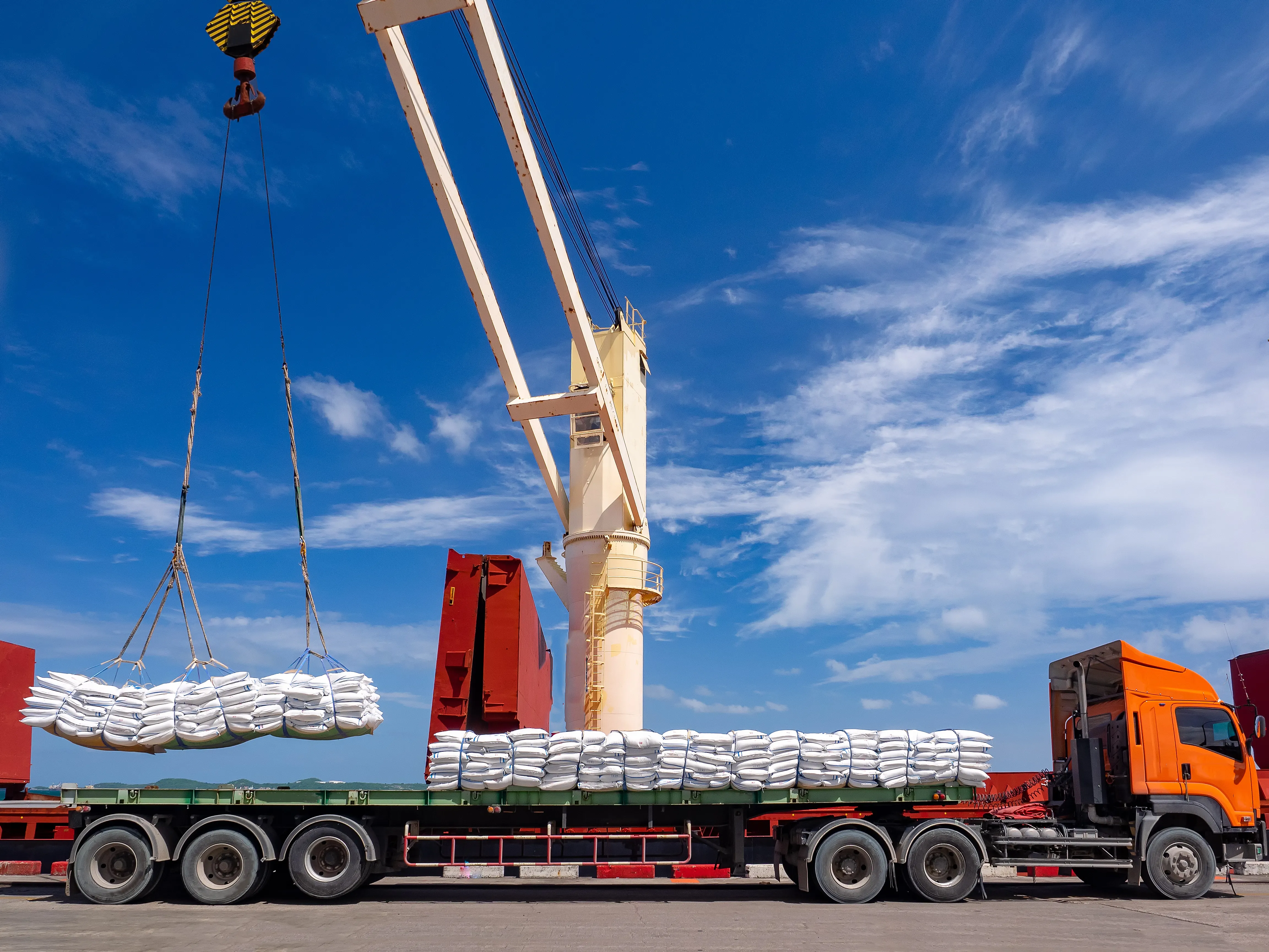 Pallets of bagged sugar being loaded onto a truck at port logistics